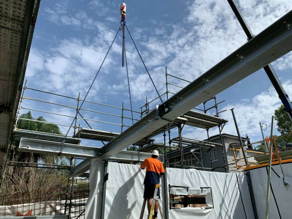 crane used at a house build, large beam being lifted into place